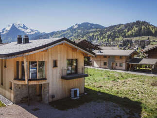 Experience modern alpine living in this stunning wooden chalet, featuring a stone base and expansive windows that capture breathtaking mountain views.
