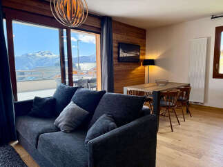 Experience breathtaking mountain views from this stunning apartment, featuring a spacious living area with a comfortable sofa and a modern dining set perfect for family meals.