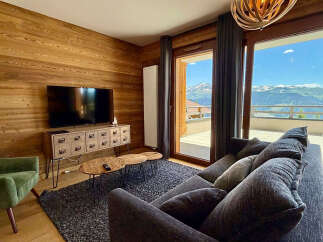 Experience breathtaking mountain views from this stunning living room, featuring a modern entertainment center and cozy seating.