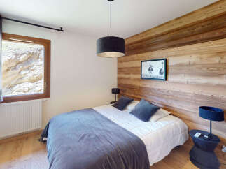 Experience cozy mountain living in this charming bedroom featuring a plush bed adorned with soft pillows and a luxurious duvet.