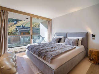 Experience luxury mountain living in this stunning bedroom featuring a plush king-sized bed with a faux fur throw, perfect for cozy nights.