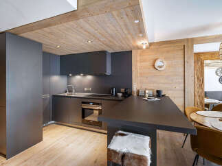 Experience modern alpine living in this stylish kitchen featuring sleek, dark cabinetry and a spacious countertop perfect for meal preparation.
