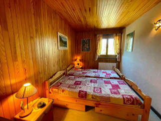 Experience cozy comfort in this charming bedroom featuring two twin beds with rustic wooden frames and patterned quilts.