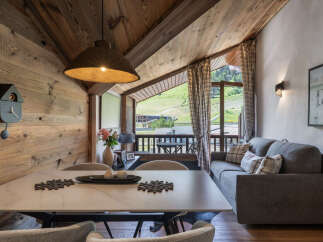 Experience cozy mountain living in this charming dining and living area, featuring rustic wood paneling and a vaulted ceiling.