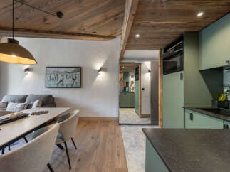Experience modern alpine living in this beautifully appointed space, featuring a spacious dining area with comfortable seating and a large pendant light, adjacent to a cozy living room with a plush sofa.