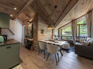 Experience alpine living in this charming mountain retreat, featuring a cozy dining area with elegant chairs and a modern kitchen with a striking green Smeg kettle.
