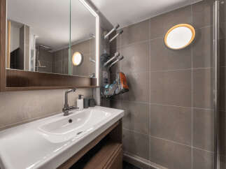 Discover modern comfort in this well-appointed bathroom, featuring a sleek vanity with a spacious sink and a large, illuminated mirror.