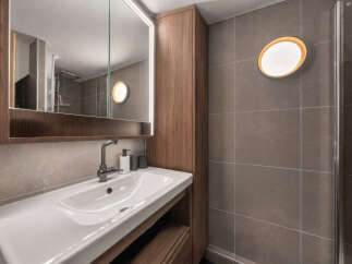 Discover modern comfort in this well-appointed bathroom, featuring a sleek vanity with a spacious sink and a large, illuminated mirror.
