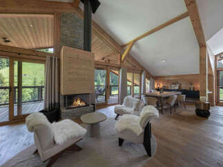 Experience luxury mountain living in this stunning chalet featuring a grand stone fireplace and expansive wooden beams.
