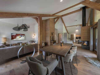 Experience luxury mountain living in this stunning chalet, featuring a spacious open-plan living and dining area with a cozy fireplace and exposed wooden beams.