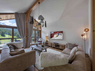 Experience luxurious mountain living in this stunning chalet, featuring a spacious living area with a large sectional sofa and a cozy fireplace.