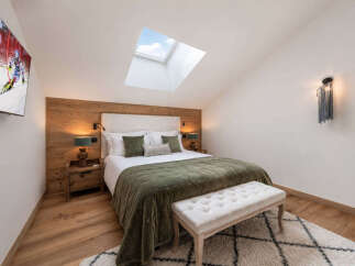Experience cozy mountain living in this charming bedroom, featuring a plush queen-size bed adorned with soft green accents and a luxurious quilted throw.