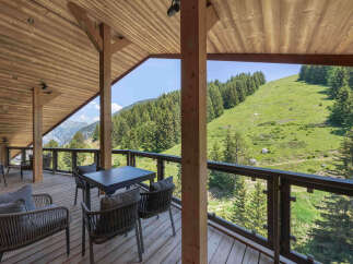 Enjoy breathtaking mountain views from this stunning wooden balcony, perfect for outdoor dining or relaxation.