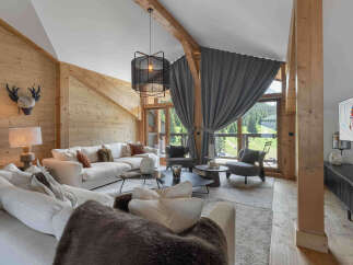 Experience luxury mountain living in this stunning chalet, featuring a spacious living area with a large sectional sofa and a cozy fireplace.