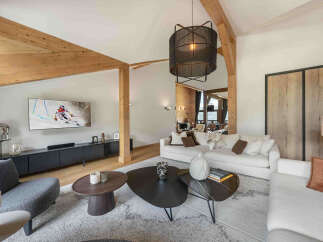 Experience luxury mountain living in this stunning living room, featuring exposed wooden beams and a vaulted ceiling that create a warm, alpine ambiance.