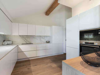 Experience modern living in this sleek white kitchen, featuring a stunning marble backsplash and integrated Bosch appliances.