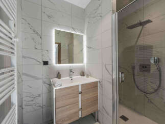 Experience modern luxury in this stunning bathroom featuring elegant marble-effect tiles and a sleek vanity with ample storage.