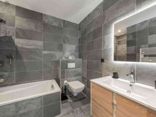 Experience modern luxury in this stunning bathroom featuring sleek, large-format grey slate tiles that create a sophisticated and spa-like atmosphere.