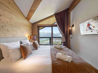 Experience luxury mountain living in this stunning bedroom featuring a plush king-size bed and breathtaking panoramic views of the Alps.