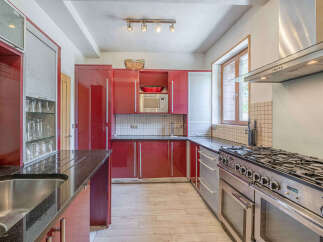 This modern kitchen features sleek, high-gloss red cabinetry that provides ample storage and a vibrant aesthetic.