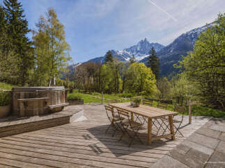 Experience ultimate relaxation with this stunning outdoor living space, featuring a rustic wooden hot tub perfect for soaking in the breathtaking mountain views.