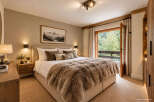 Experience ultimate comfort in this luxurious bedroom, featuring a plush fur throw and a cozy ambiance.