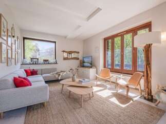 Experience breathtaking mountain views from this stunning living room, featuring a spacious sectional sofa adorned with vibrant red pillows and a cozy faux fur throw.