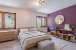 This beautifully appointed bedroom features a comfortable wooden bed with crisp white linens and a cozy grey throw.