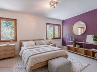 This beautifully appointed bedroom features a comfortable wooden bed with crisp white linens and a cozy grey throw.