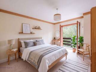 Experience serene living in this beautifully appointed bedroom, featuring a comfortable queen-size bed with plush grey linens and a cozy throw.
