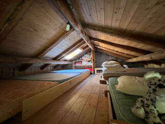 Discover this charming attic bedroom, featuring rustic wooden beams and a cozy, sloped ceiling.