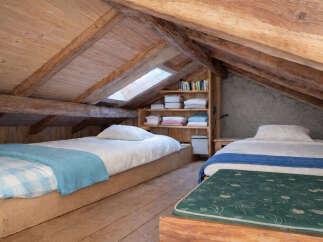 Discover this charming attic bedroom featuring two cozy single beds, perfect for guests or a family.