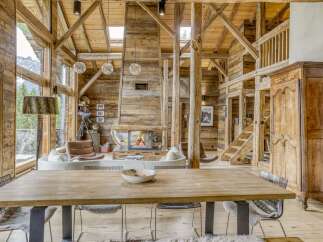 Experience rustic luxury in this stunning wooden chalet, featuring a grand stone fireplace and soaring exposed beams.
