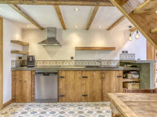 Experience rustic charm in this beautifully appointed kitchen, featuring custom wooden cabinetry and a sleek stainless steel range hood.