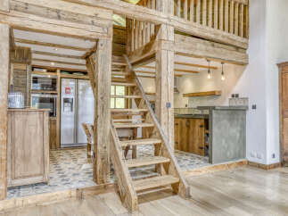 Experience rustic charm in this mountain chalet featuring a stunning wooden staircase leading to a loft.