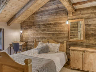 Experience rustic charm in this cozy bedroom featuring a wooden bed frame with heart cutouts and a matching bedside cabinet.