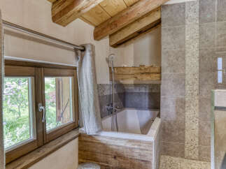 Experience rustic charm in this bathroom featuring a deep soaking tub with a wooden surround, perfect for unwinding.
