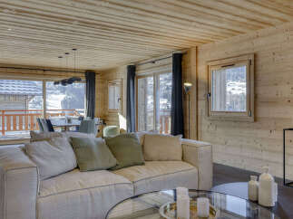 Experience luxurious mountain living in this stunning chalet, featuring a spacious open-plan living area with a comfortable sectional sofa and a modern dining set.