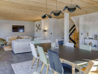 Experience modern mountain living in this stunning open-concept space, featuring a sleek dining area with comfortable seating and a spacious living room with plush sofas and a wall-mounted TV.