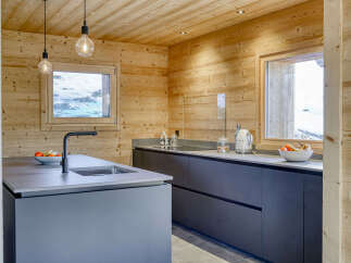 Experience modern alpine living in this stunning kitchen featuring sleek, dark cabinetry and a spacious island with a built-in sink and faucet.
