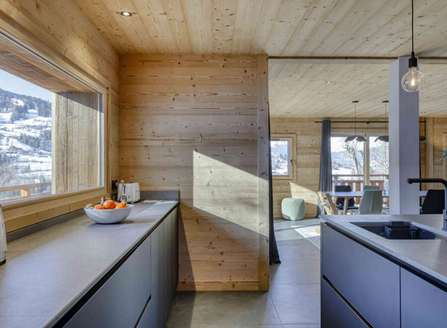 Experience modern living in this stunning mountain chalet, featuring a sleek kitchen with a large island and integrated appliances.