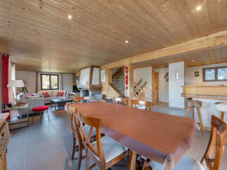 Experience cozy living in this charming mountain retreat, featuring a spacious dining area with a large wooden table perfect for family gatherings.