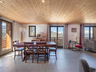 Experience breathtaking mountain views from this stunning dining and living area, featuring a spacious wooden dining table perfect for family meals.