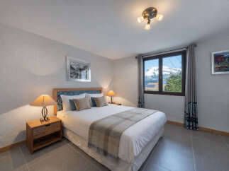 Experience cozy mountain living in this charming bedroom, featuring a comfortable queen-size bed adorned with plush pillows and a warm plaid throw.