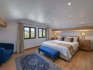 Experience serene mountain living in this charming bedroom, featuring a comfortable king-size bed adorned with plush pillows and a cozy plaid throw.