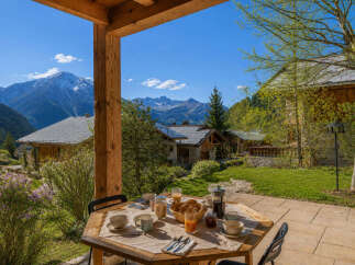 Enjoy a delightful breakfast on this charming wooden terrace, offering breathtaking views of snow-capped mountains and lush green valleys.