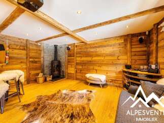 Experience rustic charm in this cozy living space featuring a modern wood-burning stove set against a stone hearth.