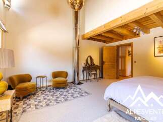 Experience luxury mountain living in this stunning bedroom featuring a spacious king-size bed and a cozy seating area with two plush armchairs.