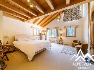 Experience rustic charm in this spacious bedroom featuring a large, comfortable bed and exposed wooden beams on the vaulted ceiling.