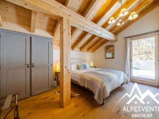 Experience cozy mountain living in this charming bedroom featuring exposed wooden beams and a vaulted ceiling.